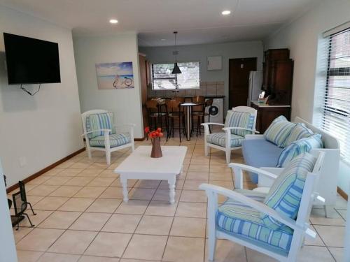 a living room with chairs and a couch and a table at Travellers Treat Agulhas 8 sleeper in Agulhas