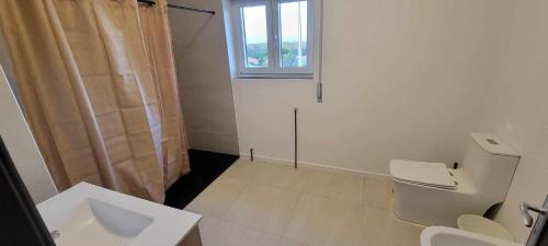 a bathroom with a toilet and a sink and a window at Casa do Alto in Nadadouro