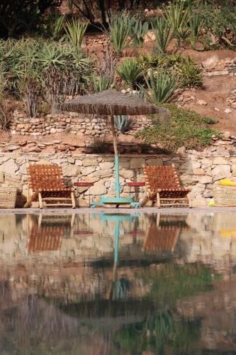 two chairs and an umbrella next to a pool at Paradis Nomade in Azrarag