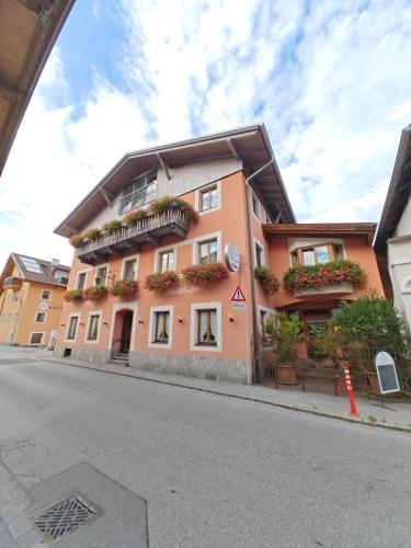 an orange building with flowers on the balconies on a street at Gasthof Zum Stollhofer in Inzing