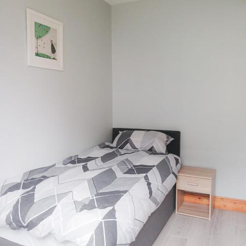 a bedroom with a bed with a black and white comforter at Seamount Holiday Village No 26 by Trident Holiday Homes in Courtown