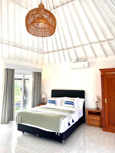 a bedroom with a large bed and a chandelier at Greenhouse Villa in Kerobokan