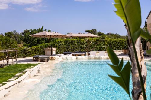 a swimming pool with two umbrellas and a pool at Oasi mandrevecchie in Giarratana