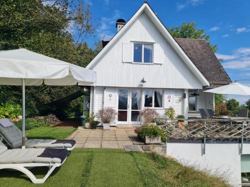 a white house with lawn chairs and an umbrella at Mont Blanc Chalet in Grandevent
