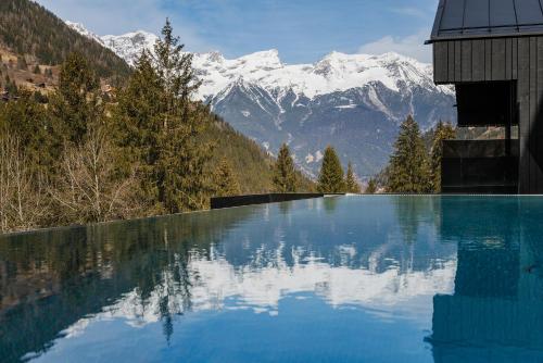 a swimming pool with snow covered mountains in the background at Paznauner Villen - Villa I in Kappl