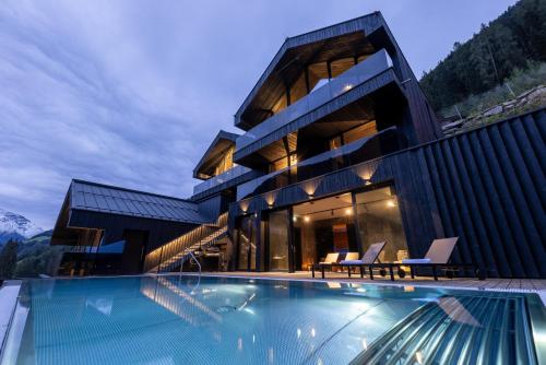 a house with a swimming pool in front of a building at Paznauner Villen - Villa I in Kappl