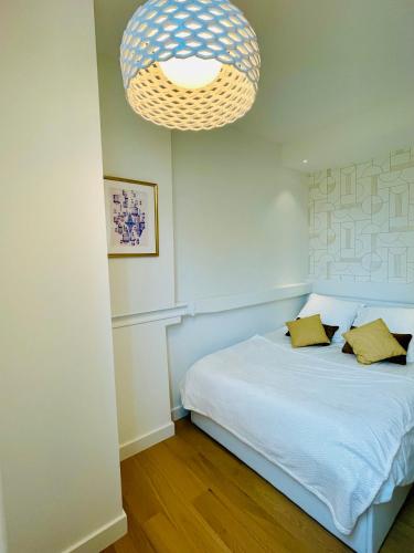 - une chambre avec un lit blanc et un lustre dans l'établissement Appartements de charme du Général Leclerc - Place d'Erlon - Hypercentre - Gare - Reims, à Reims