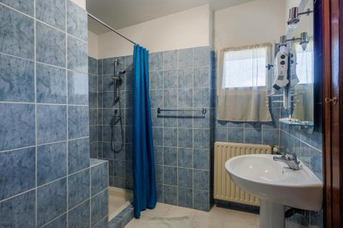 une salle de bain carrelée bleue avec un lavabo et une douche dans l'établissement Le Viguier - Maison avec terrasse vue montagne, à Monieux