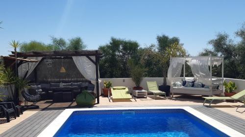 a swimming pool with chairs and a gazebo at Quinta dos Migueis in Altura