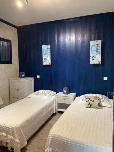 deux lits dans une chambre aux murs bleus dans l'établissement Villa Aquarelle, à La Garonnette-Plage