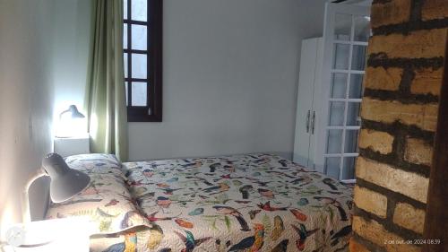 a bedroom with a bed and a lamp and a window at Bangalô Lygia in Florianópolis