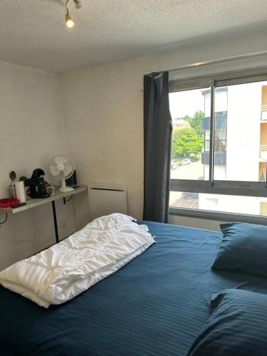 une chambre avec un lit avec une couverture bleue et une fenêtre dans l'établissement Studio 319 Les Logis de Paray Proche Gares, à Paray-le-Monial