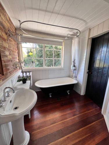 a bathroom with a tub and a sink and a window at The Coachhouse - studio apartment in Goulburn