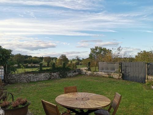 een houten tafel en stoelen in een tuin bij Épi Cottage in Coulgens