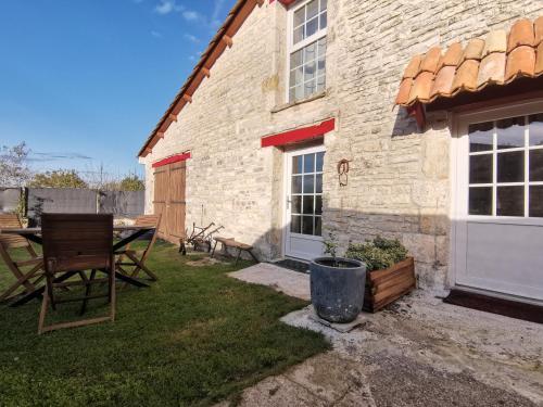 een stenen huis met een tafel en een patio bij Épi Cottage in Coulgens