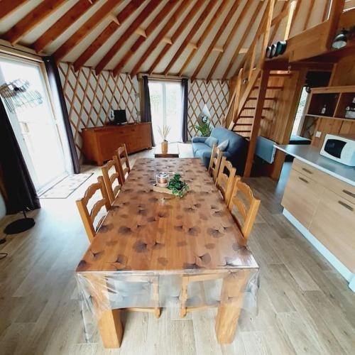 - une grande table en bois avec des chaises dans l'établissement Yourte contemporaine, à Vallons-de-l'Erdre