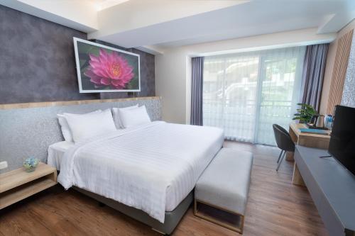 ein Schlafzimmer mit einem großen weißen Bett und einem Schreibtisch in der Unterkunft Kamala Bali Resort in Nusa Dua