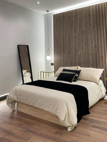 una camera da letto con un grande letto con cuscini bianchi e neri di Plaza Mayor de Salamanca Apartamentos a Salamanca