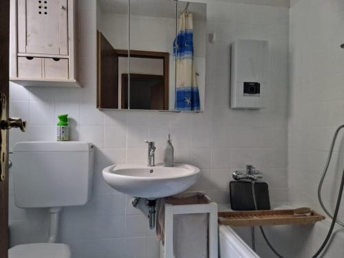 a white bathroom with a sink and a toilet at Apartment am Rodelberg in Braunlage
