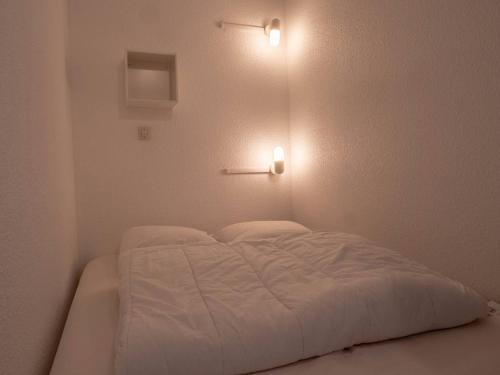 - un lit blanc avec deux lumières sur le mur dans l'établissement Charmant appart 23m² à Méribel Mottaret avec balcon, pied des pistes, idéal famille - FR-1-355-194, à Les Allues