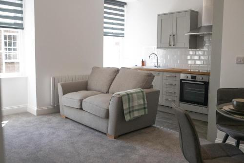 a living room with a couch and a kitchen at No.9 Priory House, Bodmin in Bodmin