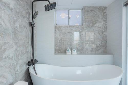 a white bath tub in a bathroom with a mirror at 3H GRAND HOTEL Vũng Tàu in Vung Tau