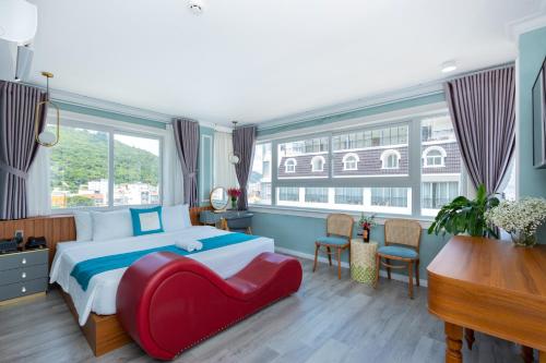 a bedroom with a large bed and a red chair at 3H GRAND HOTEL Vũng Tàu in Vung Tau
