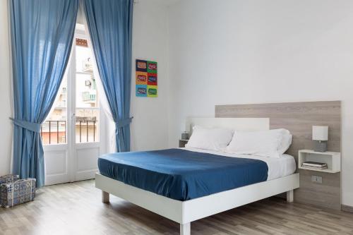a bedroom with a bed with blue curtains and a window at B&B Vitruvio Suites in Formia