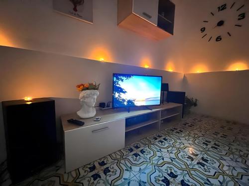 a living room with a television and a clock on the wall at Suite - Villa La Terrazza Sul Mare in Trabia