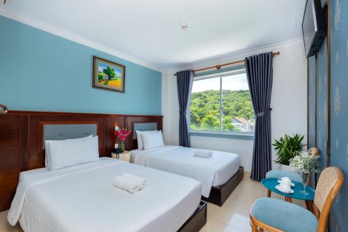 a hotel room with two beds and a window at 3H GRAND HOTEL Vũng Tàu in Vung Tau