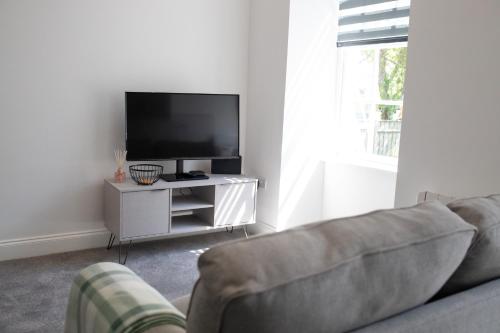 a living room with a couch and a flat screen tv at No.9 Priory House, Bodmin in Bodmin