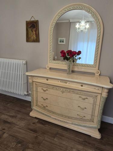 a dresser with a mirror and a vase with flowers on it at Il sogno degli angeli in Santa Maria degli Angeli