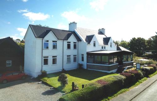 a white house with a car parked in the driveway at Atholl House Skye in Dunvegan