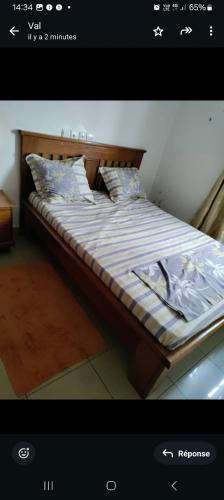 a bed with a wooden frame and pillows on it at Val Appart 2 in Douala