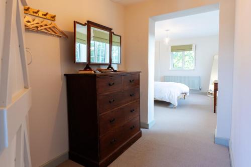 a bedroom with a dresser with a mirror and a bed at Stable Flat on Gorgeous Rural Farm in Goadby Marwood