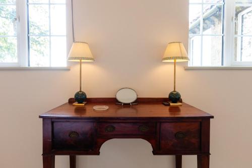 two lamps on top of a wooden desk with a mirror at Stable Flat on Gorgeous Rural Farm in Goadby Marwood