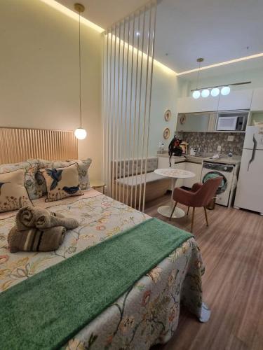 a bedroom with a large bed and a kitchen at Hortênsia Confort Stúdio Rio in Rio de Janeiro