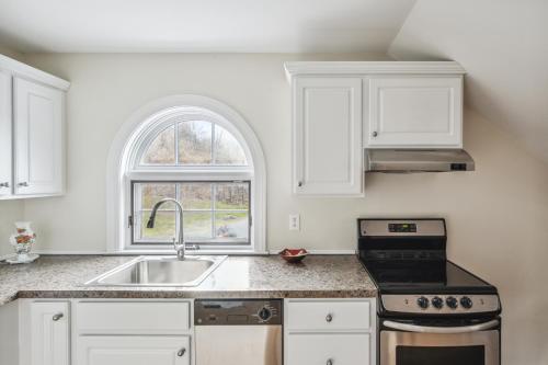 a kitchen with white cabinets and a sink at Tigertown Lodge home in White River Junction