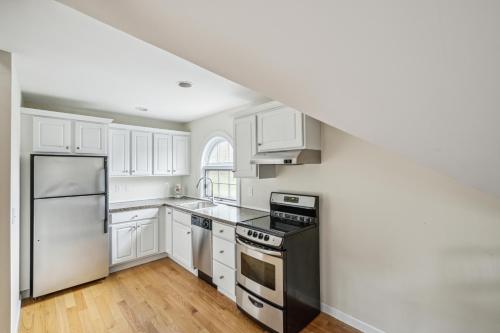 a kitchen with white cabinets and a black refrigerator at Tigertown Lodge home in White River Junction