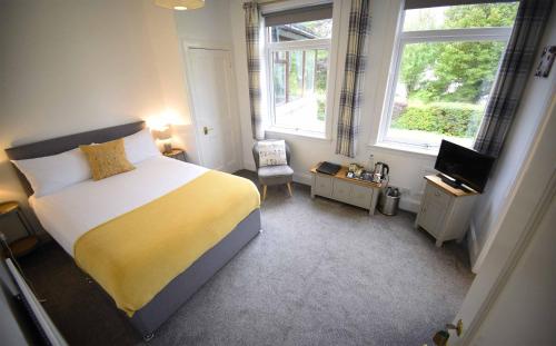 a bedroom with a bed and a tv and two windows at Atholl House Skye in Dunvegan