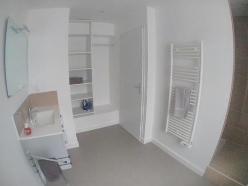 une salle de bain blanche avec un lavabo et un miroir dans l'établissement Grand T2 centre-ville, calme, lumineux et spacieux, 1 chambre, 1 à 5 pers, climatisation, wifi, parking libre et gratuit, à Lorient