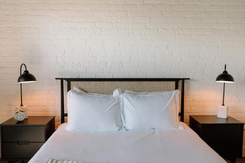 a bed with white pillows and two tables with lamps at Unit A, The Kroger Lofts in Charlevoix