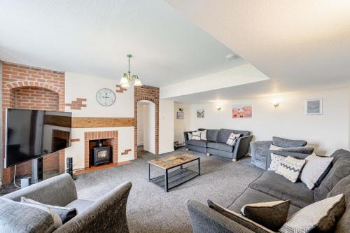 a living room with couches and a fireplace at Auchenlarie Farmhouse in Gatehouse of Fleet