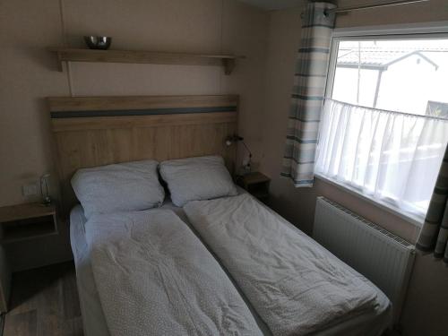 un letto con due cuscini e una finestra in una stanza di Chalet ZeeWave I 6 Personen I Renesse I Niederlande a Renesse
