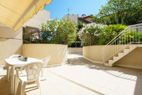 d'une terrasse avec une table, des chaises et des escaliers. dans l'établissement L'impérial, terrasse, à Menton
