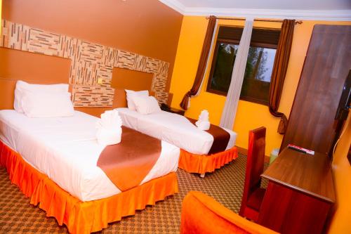two beds in a hotel room with yellow walls at The Country Inn Hotel in Kigali