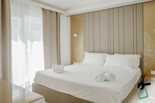 a bedroom with a large white bed with towels on it at Hotiday Apartments Cefalù in Cefalù