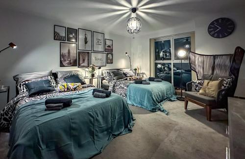 a bedroom with two beds and a chair and a clock at Brand New Scotland home 3rooms near Glasgow in Clydebank