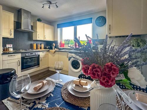 a kitchen with a table with a vase of flowers at Brand New Scotland home 3rooms near Glasgow in Clydebank