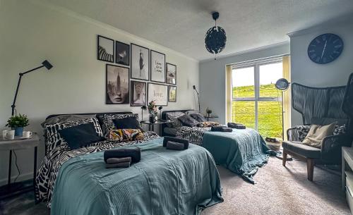 a bedroom with two beds and a clock on the wall at Brand New Scotland home 3rooms near Glasgow in Clydebank